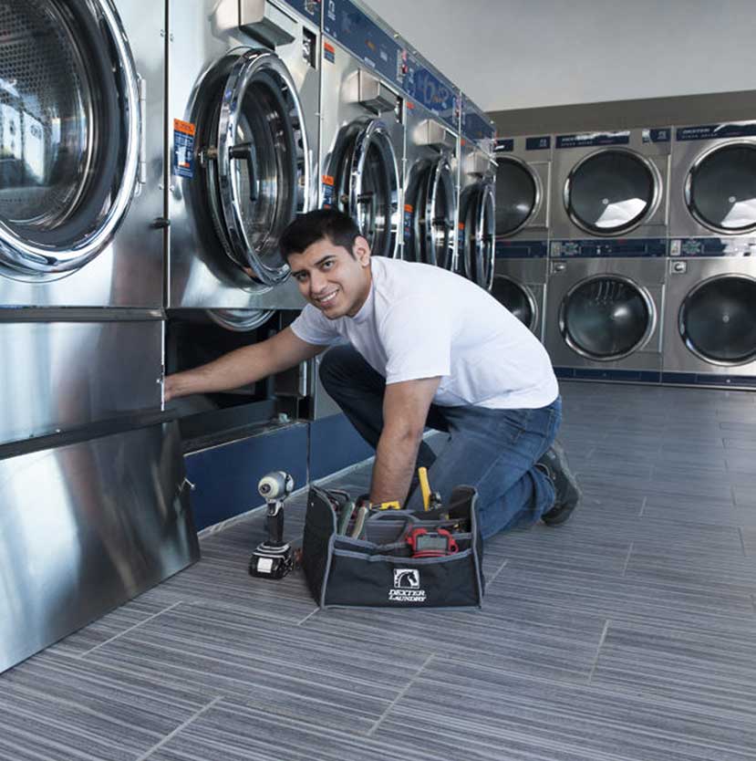 Technician repairs a washing machine with toolbox nearby